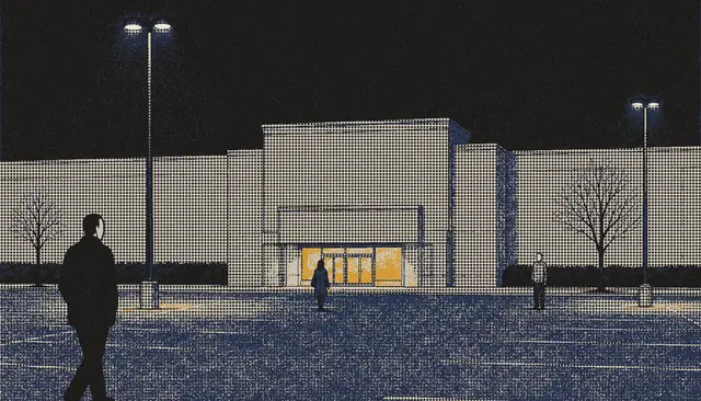 A department store at night across an empty car park, its doorway lit